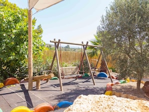 A wooden swing set in a garden with a view of a hilly landscape.