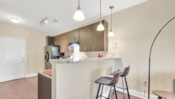 Une cuisine moderne dotée d’un îlot central, de tabourets de bar, de luminaires suspendus et d’armoires en bois.