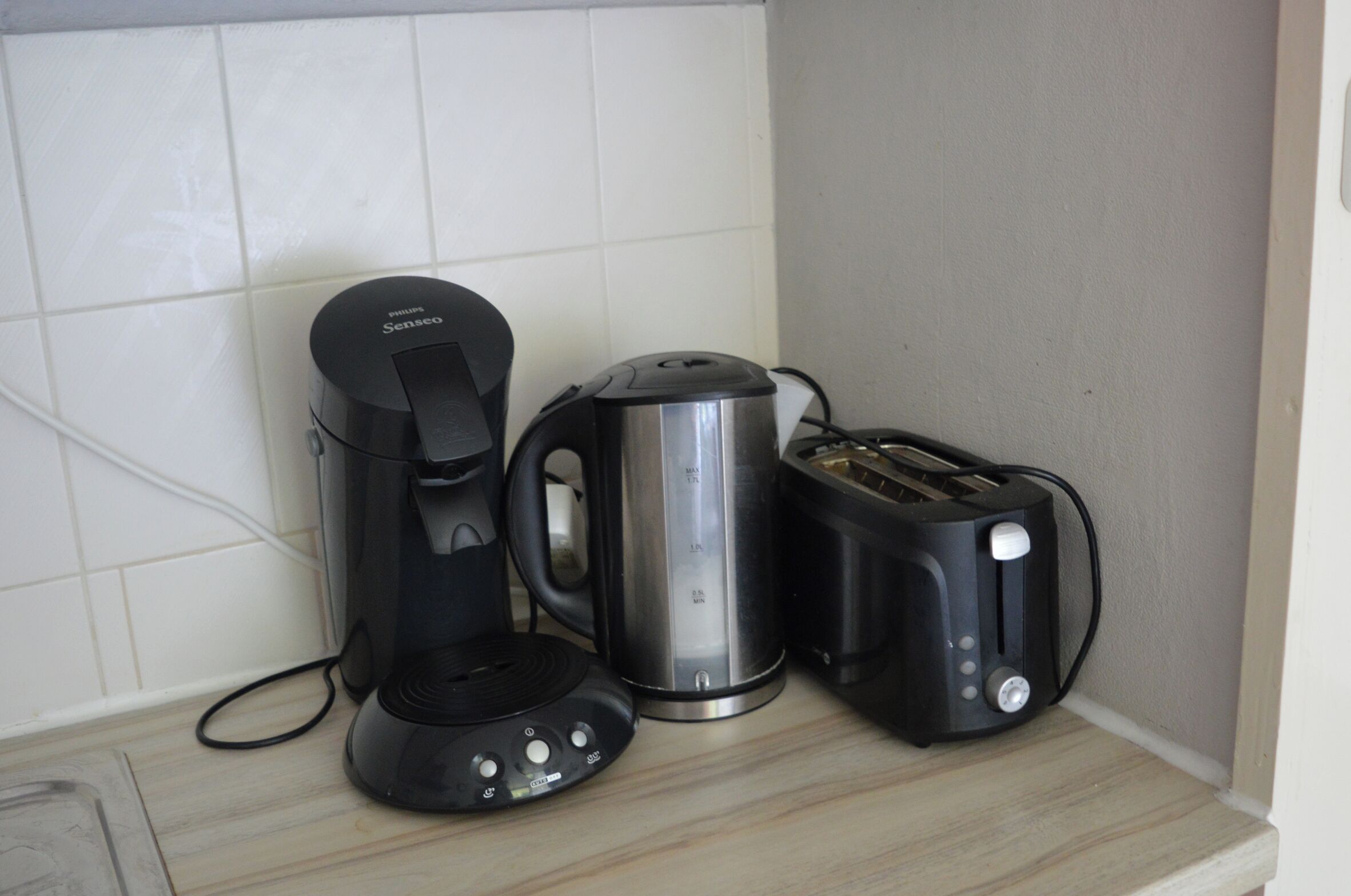 Un piano di lavoro in cucina con una macchina da caffè, un bollitore e un tostapane.