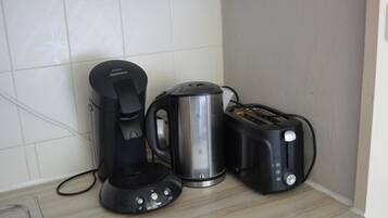 Un piano di lavoro in cucina con una macchina da caffè, un bollitore e un tostapane.