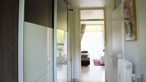 Un couloir menant à un salon équipé d’un canapé et d’un radiateur.