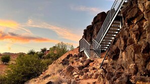 A staircase built into a rocky hillside with a metal railing, surrounded by dry vegetation and a sunset sky. - Spacious Home with Hot Tub & Splash Pad Near Zions (La Verkin)
