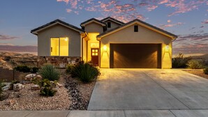 A two-story house with a garage, a driveway, and a landscaped garden with rocks and plants. - Spacious Home with Hot Tub & Splash Pad Near Zions (La Verkin)