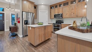 A modern kitchen with wooden cabinets, stainless steel appliances, and a white countertop. - Spacious Home with Hot Tub & Splash Pad Near Zions (La Verkin)
