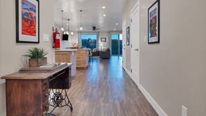 A spacious hallway with a wooden desk, a plant, and framed artwork on the walls. - Spacious Home with Hot Tub & Splash Pad Near Zions (La Verkin)