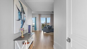 Un salon moderne avec un canapé gris, une table basse et un grand tableau abstrait accroché au mur.