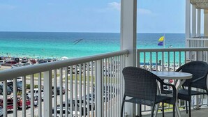 Un balcon avec vue sur la plage et l’océan. On y trouve deux fauteuils en osier et une petite table.