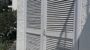 A building with two large, white, shuttered doors with horizontal slats. - Basic studio in Canyelles with communal terrace + private outdoor parking. (Roses)
