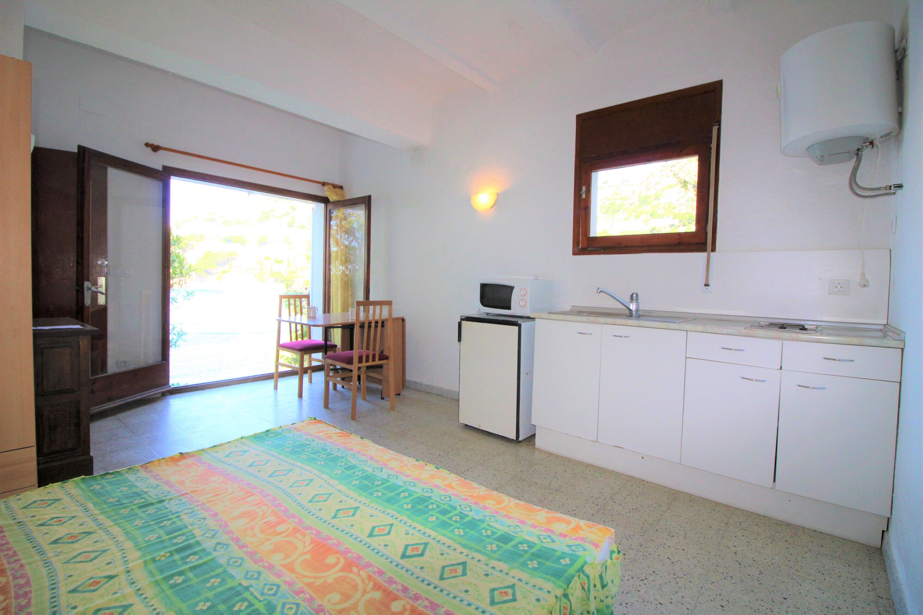 A small, bright kitchen with white cabinets, a microwave, and a window above the sink.