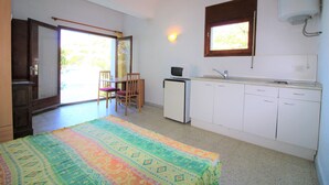 A small, bright kitchen with white cabinets, a microwave, and a window above the sink. - Basic studio in Canyelles with communal terrace + private outdoor parking. (Roses)