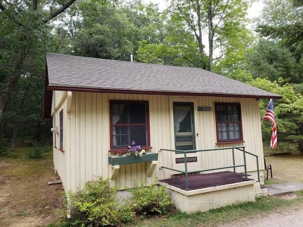 A small, single-story building with a porch, a flag, and a mailbox.