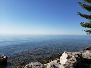 A clear view of a rocky shoreline with calm water extending to the horizon.
