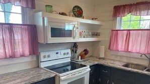 A kitchen with dark cabinets, a white stove, a microwave, and a sink. - The Jackson House of Gamaliel (Gamaliel)