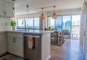 Una cocina moderna con una isla grande, un comedor con vistas y un balcón con vista a la ciudad.