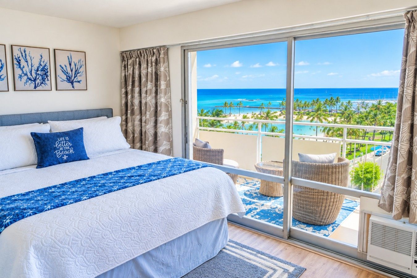 Ein Hotelzimmer mit Bett, Blick auf den Strand und einem Balkon mit Korbmöbeln.