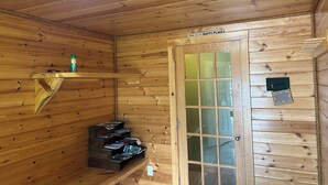 A wooden cabin interior with a wooden door labeled "THIS IS MY HAPPY PLACE," a shelf with a bottle, and a small wooden bench. - Private quiet home close to Sunday River, Bethel village, and summer recreation  (Bethel)