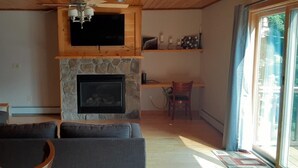 A living room with a stone fireplace, a television mounted above it, and a sofa. - Private quiet home close to Sunday River, Bethel village, and summer recreation  (Bethel)