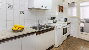 A kitchen with white cabinets, a double sink, a stove, and a microwave. There is a bowl of lemons on the counter. - Palmeras by Interhome (Blanes)