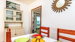 A dining area with a table set for four, featuring a fruit bowl, plates, and cutlery. - Palmeras by Interhome (Blanes)
