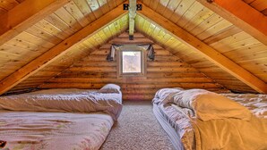A cozy attic bedroom with two beds, a small window, and wooden beams. - Charming Montana Retreat w/ Mountain Views! (Checkerboard)