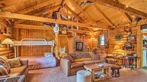 A cozy log cabin interior with a bunk bed, a sofa, a coffee table, and various hunting trophies on the walls. - Charming Montana Retreat w/ Mountain Views! (Checkerboard)