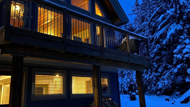A two-story wooden house with large windows and a balcony, surrounded by snow-covered trees. - The Snowshoe House - 3 bed 2 bath cabin + hot tub (Agassiz)
