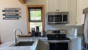 A modern kitchen with white cabinets, stainless steel appliances, and a granite countertop. - The Snowshoe House - 3 bed 2 bath cabin + hot tub (Agassiz)