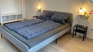 Ein Schlafzimmer mit Bett, Nachttischen, einer Lampe und einem Wandregal.