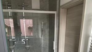 Ein modernes Badezimmer mit Duschkabine aus Glas, einem weißen Waschbecken und Holzboden.