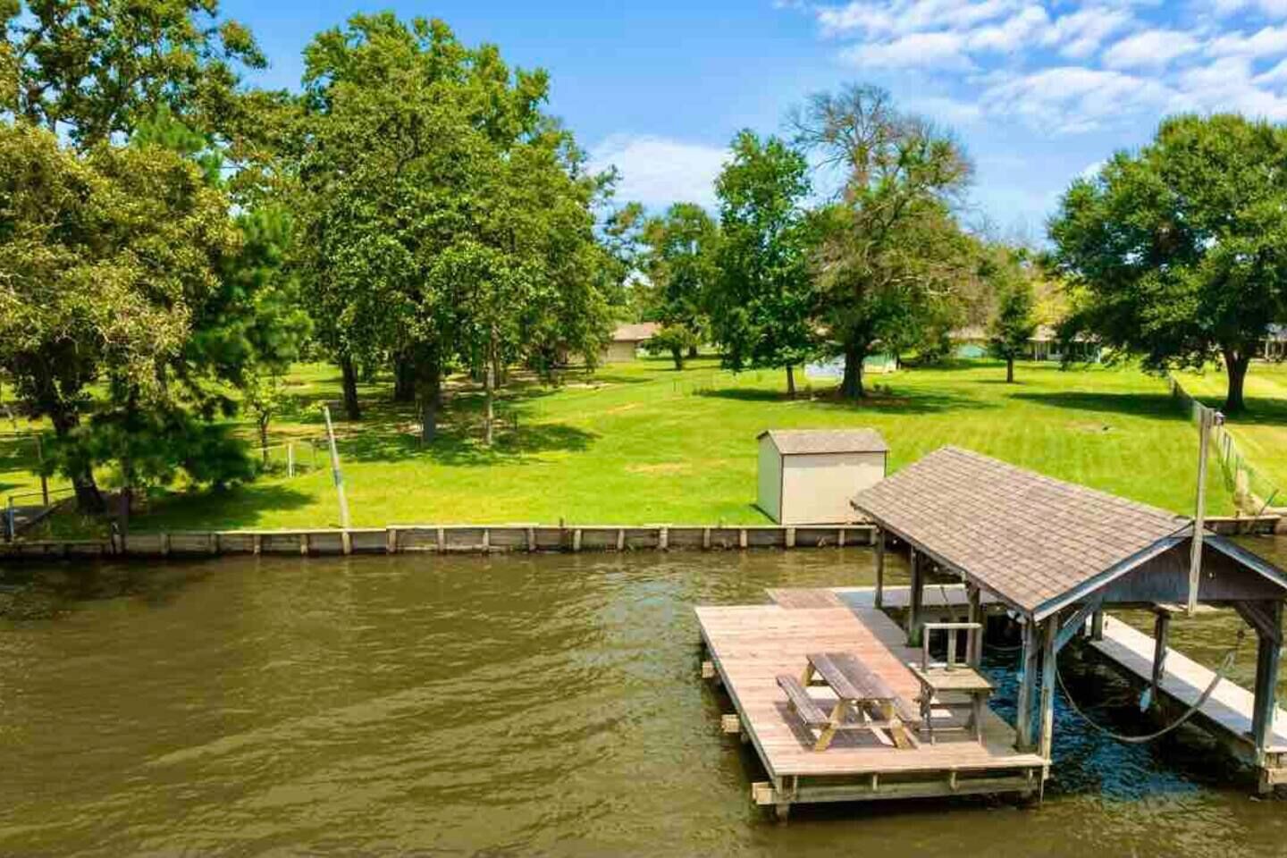 A riverside dock with a covered seating area and a small shed.