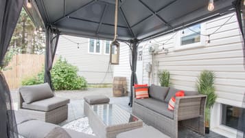 Relax in a sheltered outdoor space with wicker sofas and a coffee table, perfect for conversation and leisure.