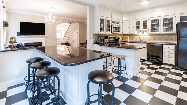 Une cuisine moderne avec un îlot central, des tabourets de bar et un carrelage à motifs géométriques.