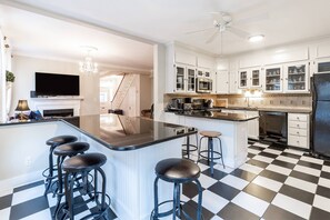 A modern kitchen with a central island, bar stools, and a checkered floor.