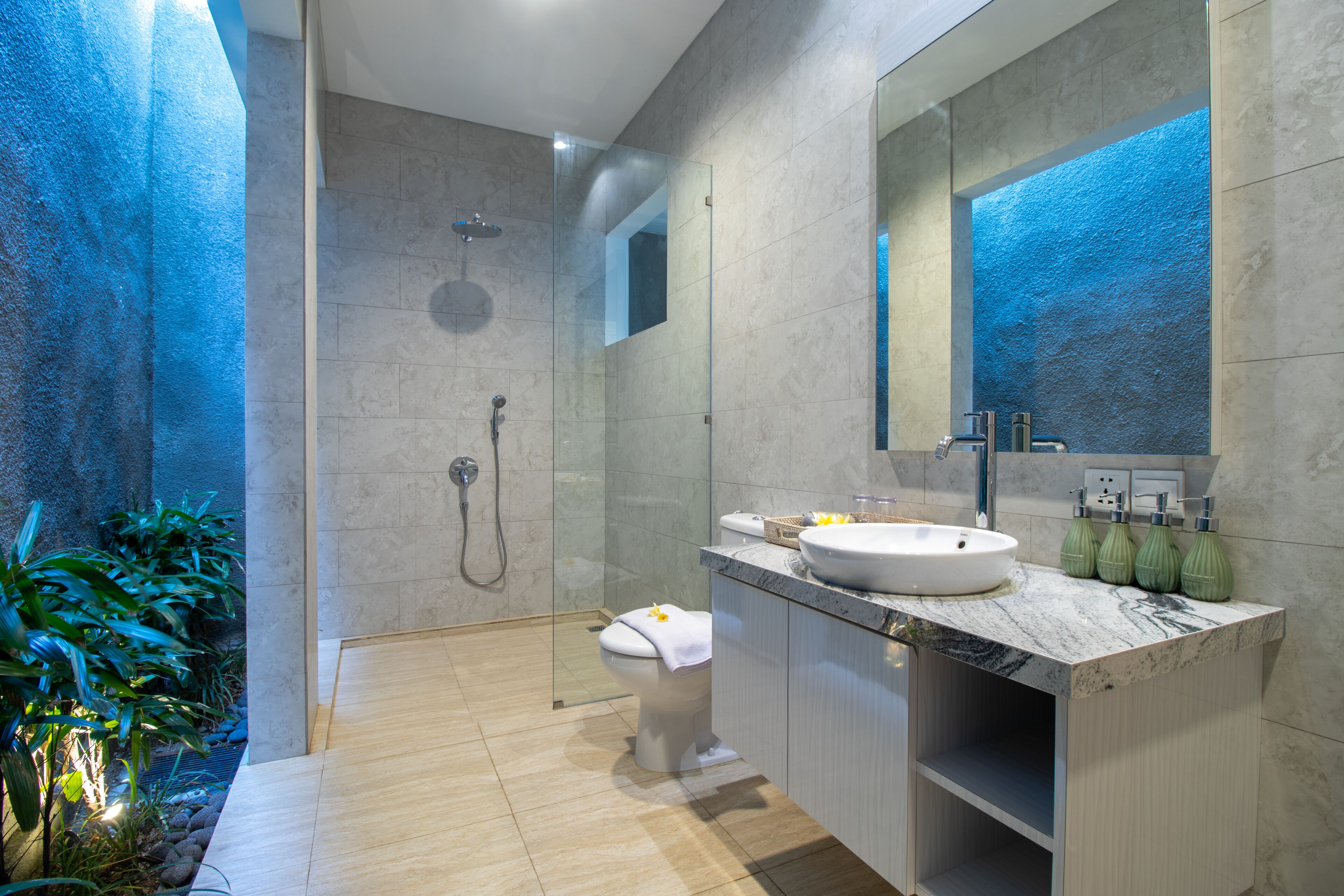 A modern bathroom with a glass-enclosed shower, a marble sink, and a large mirror.