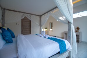 Uma cama de dossel com cortinas, roupa de cama branca e detalhes azuis, uma porta de madeira e uma pequena estátua em um criado-mudo.