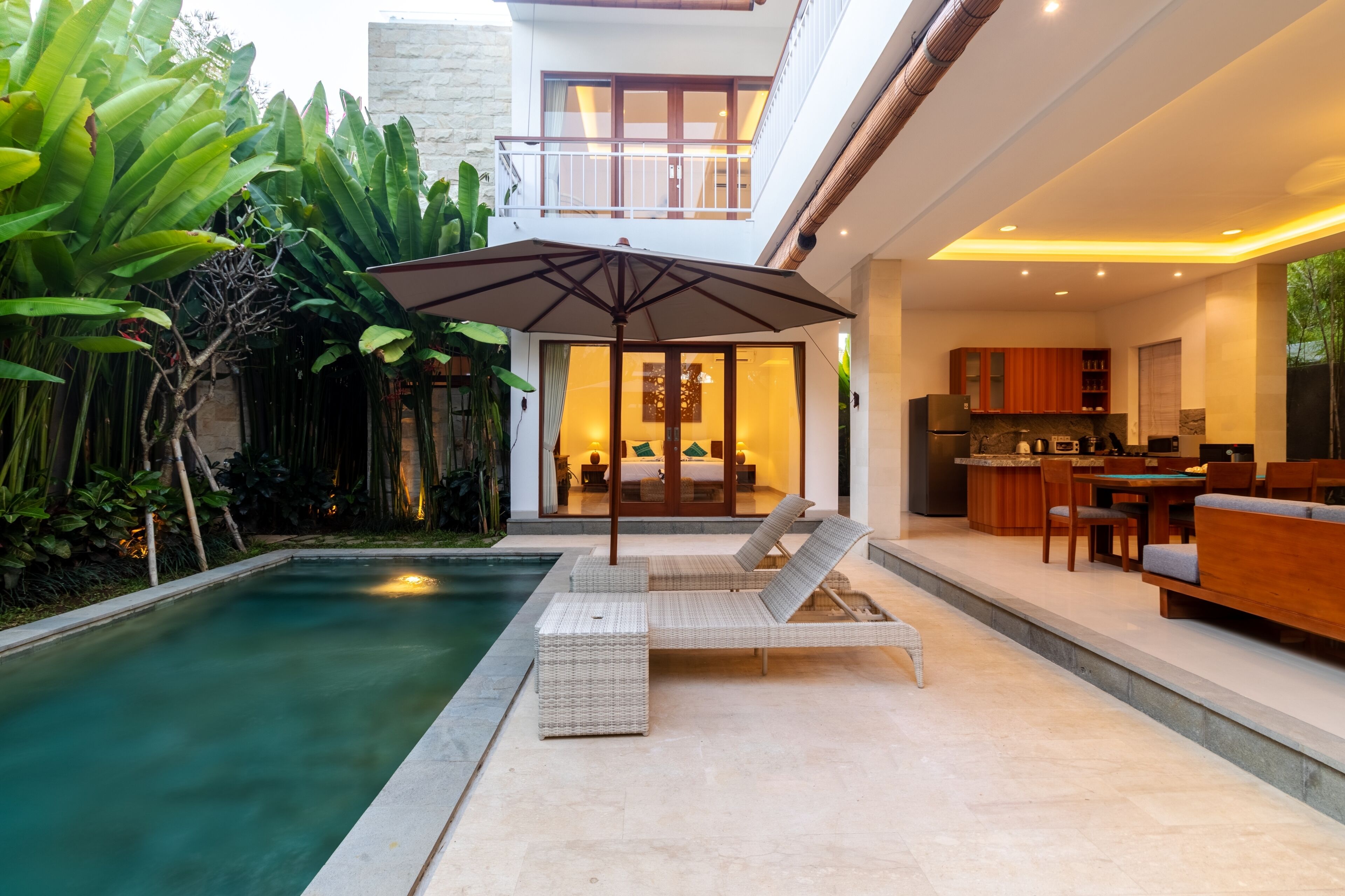 Una casa moderna con piscina, area salotto esterna e angolo cottura.