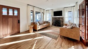 A spacious living room with a fireplace, wooden flooring, and large windows. - Fully Renovated, Charming Craftsman Home in Downtown Paso Robles Wine Country (Paso Robles)
