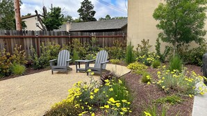 A backyard with two Adirondack chairs, a gravel patio, and a variety of yellow flowers. - Fully Renovated, Charming Craftsman Home in Downtown Paso Robles Wine Country (Paso Robles)