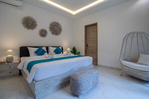 A modern bedroom with a large bed, bedside tables, a wicker chair, and decorative wall art.