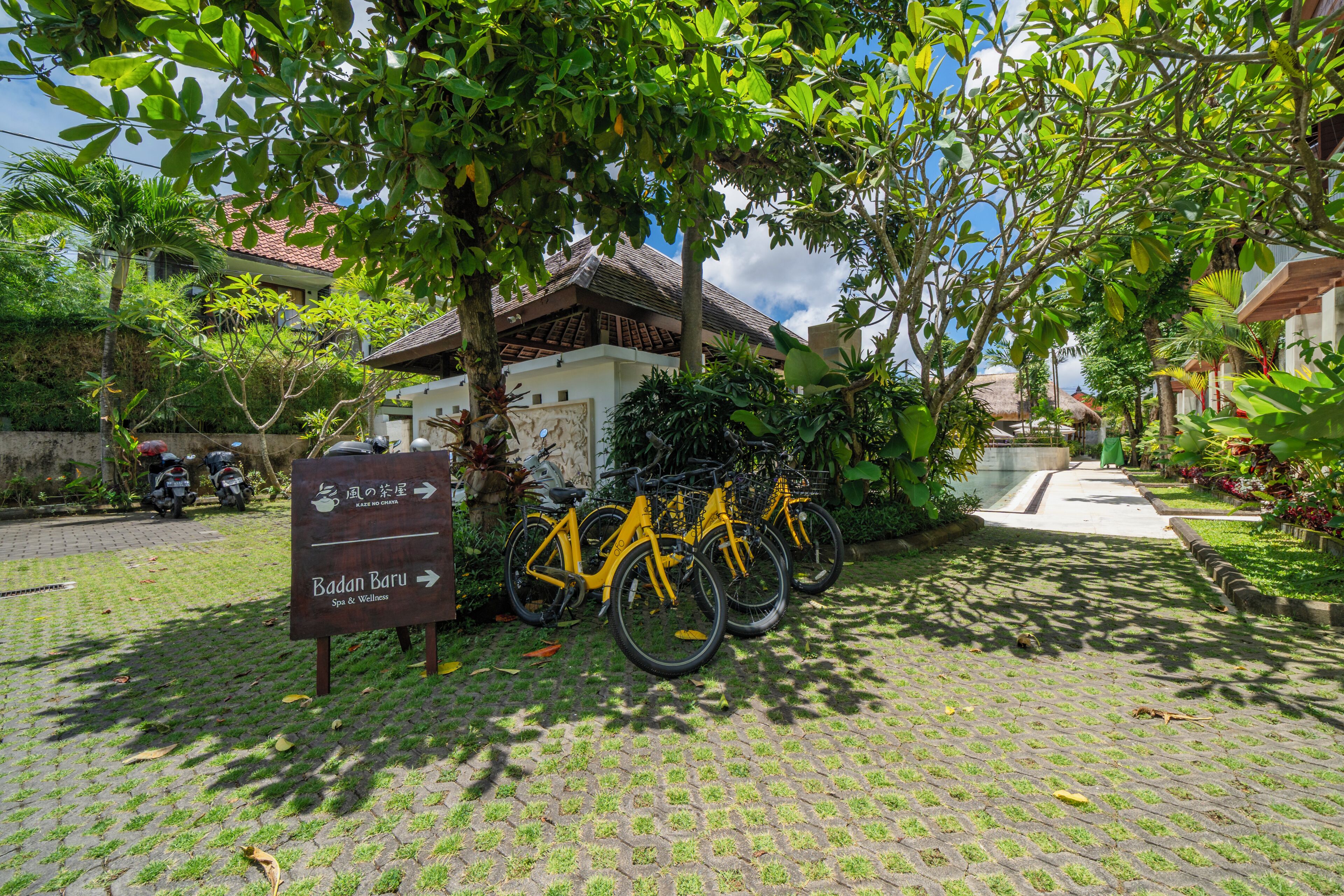 A paved area with a sign indicating a spa and wellness center, surrounded by greenery and bicycles.