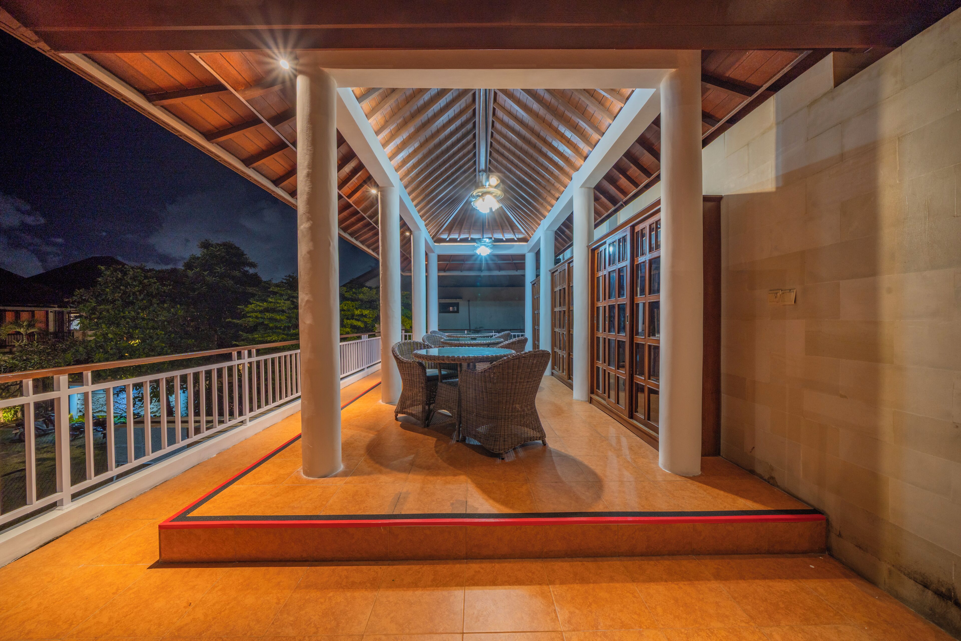 A covered outdoor area with a table and chairs, a wooden ceiling, and a view of the outdoors.