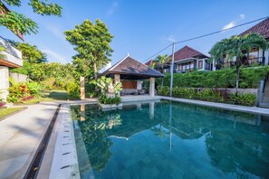 A swimming pool with a gazebo, surrounded by lush greenery and residential buildings.