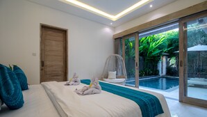 Ein Schlafzimmer mit einem großen Bett, einer Holztür, einem Korbstuhl und Blick auf einen Swimmingpool.