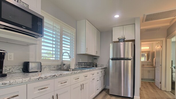A modern kitchen with white cabinets, a stainless steel refrigerator, a microwave, and a toaster. - GORGEOUS 1 BED GUEST HOME (Alpine)