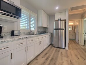 A modern kitchen with white cabinets, a stainless steel refrigerator, a microwave, and a toaster.