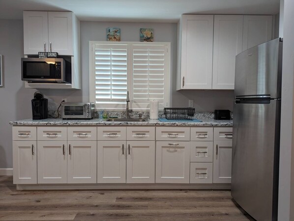 A kitchen with white cabinets, a stainless steel refrigerator, a microwave, and a toaster. - GORGEOUS 1 BED GUEST HOME (Alpine)