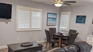 A modern living room with a leather sofa, a dining table with chairs, a ceiling fan, and artwork on the walls. - GORGEOUS 1 BED GUEST HOME (Alpine)