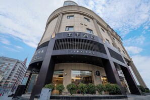 Un hotel con fachada curva, grandes ventanales y un cartel que indica que es un Jihotel.