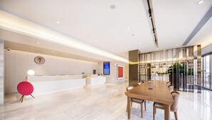 Un hall d’hôtel moderne avec un comptoir d’accueil, une grande table de conférence en bois et une cloison en verre.