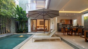 A modern house with a swimming pool, a lounge chair, and a dining area. - Sayang Sanur Villa VII (Denpasar)